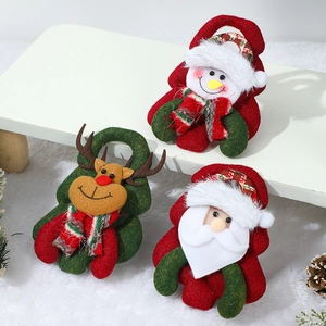 Three plush Christmas tree ornaments featuring Santa, Snowman and Reindeer on white fur