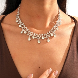 Close-up of elegant silver necklace with rhinestone bow and teardrop pendants on model