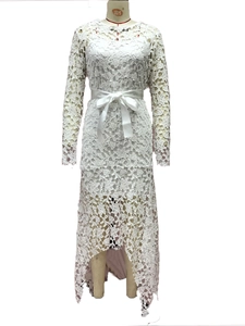 Detail of white lace dress featuring long sleeves and an irregular high-low hemline
