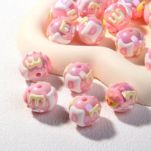 Close-up of pink acrylic hand-painted beads with letters for DIY jewelry making
