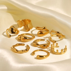 Set of nine golden irregular geometric rings on beige silk fabric with soft lighting