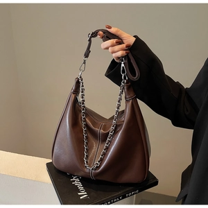 Detail of dark brown leather hobo bag with silver chain and visible stitching