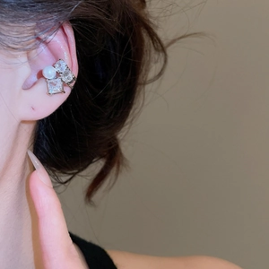 Macro detail of silver ear cuff with zircon flower and pearl on a model's ear