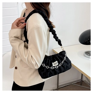Detail of black pleated fabric texture with silver flower chain on shoulder bag