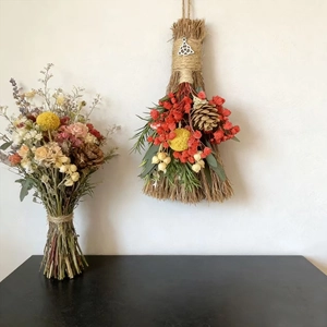 Decorative witch broom with dried flowers, pine cones and rustic bouquet for holiday decor