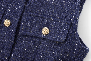 Detailed close-up of navy tweed fabric with metallic sequins and golden buttons