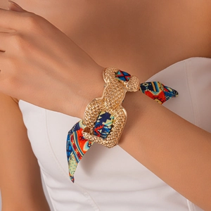 Detail of bohemian printed silk scarf wrapped with textured gold metal clasp bracelet