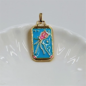 Detail of a rectangular gold-plated tarot pendant with blue enamel and pink jellyfish design