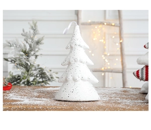 Sparkling white Christmas tree ornament with silver glitter and ribbon on a snowy table