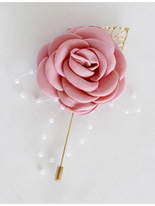Gros plan de la boutonnière rose en satin avec feuilles dorées et perles blanches