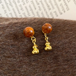 Gros plan de boucles d'oreilles vintage en ambre acrylique avec pendentifs gourde dorés