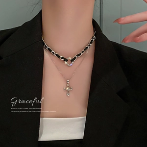 Double-layered necklace featuring a black faux leather choker and silver cross pendant