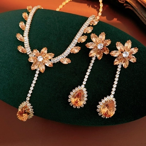 Exquisite gold flower jewelry set with amber gemstones on dark green velvet background