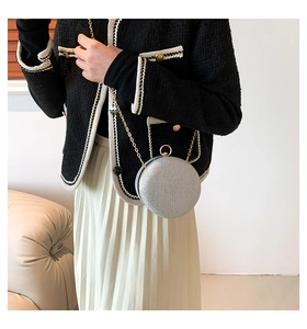 Close-up of a silver glitter sphere evening bag with a gold chain strap on a model