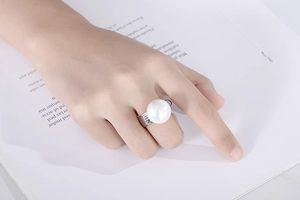 Macro detail of hammered silver steel ring featuring a large white round pearl