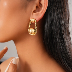 Detalle de pendientes de bola bañados en oro de 18K con diseño plisado en modelo femenino