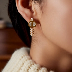 Detailed view of gold plated pearl earrings with crystal accents on a model's ear