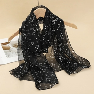 Detail of lightweight black chiffon scarf featuring white music note patterns and sheer texture