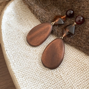 Detail view of vintage wooden drop earrings on a textured ceramic plate and fabric