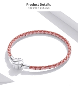 Macro detail of pink woven leather bracelet with silver flower clasp on white background