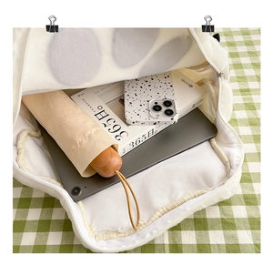 Top-down view of white plush bag interior showing large capacity for tablet and umbrella