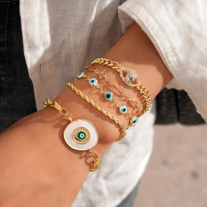 Ensemble de cinq bracelets bohèmes dorés avec breloques œil bleu et strass brillants