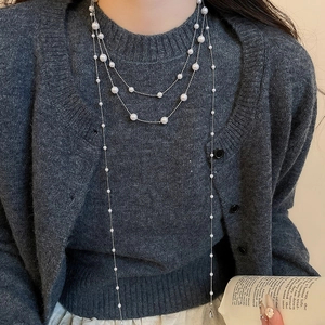 Detail einer eleganten mehrlagigen langen Perlenkette mit Silberkette an einem Model