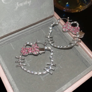 Macro shot of sparkling crystal kitty earrings with pink bows in a luxury jewelry box