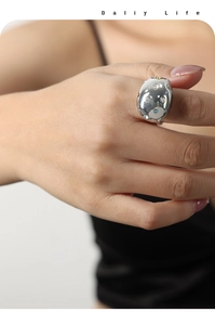 Detailed view of silver oval ring with multi-colored gemstones on a model's finger