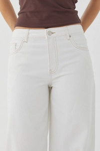 Gros plan détaillé du jean blanc à taille haute avec poches et bouton métallique