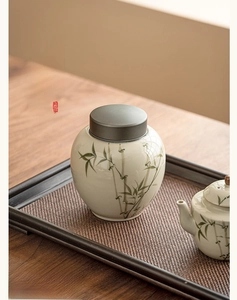 Detailed close-up of a white ceramic tea canister with hand-painted green bamboo motif