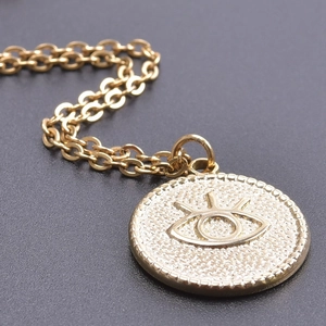 Macro shot of gold Evil Eye coin pendant with embossed details and textured edges