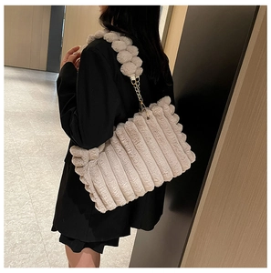 Detail of beige plush tote bag with wavy texture and woven metal chain strap