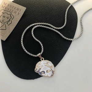 Close-up of Venus pendant necklace with purple enamel details on a black display pad