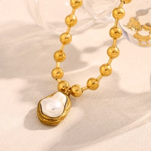 Baroque pearl necklace with 18K gold-plated beads and irregular pendant on beige surface