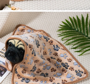 Macro detail of khaki pet blanket featuring blue paw prints on soft coral fleece fabric
