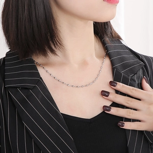 Gros plan d'un collier chaîne à perles en acier inoxydable porté par un modèle