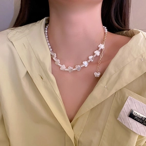 Detailed view of an irregular pearl heart necklace with golden chain on a female model