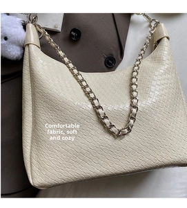 Close-up of cream woven texture shoulder bag with chain strap and fluffy charm