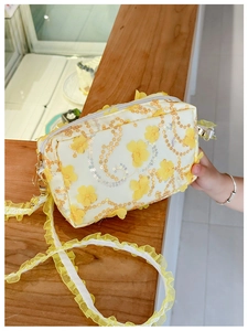 Detail of floral crossbody bag featuring yellow flower applique and ruffled shoulder strap