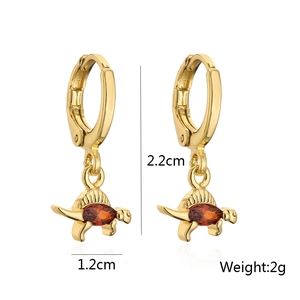 Detail shot of golden dinosaur earring with red zircon, dimensions 2.2cm by 1.2cm