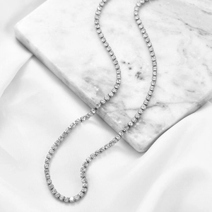 Einreihige 3mm Silber-Tennis-Halskette mit Zirkonia auf weißem Marmor und Seide