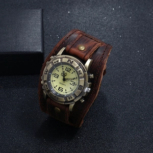 Detail of a brown leather punk watch with bronze rivets and cream dial on dark background