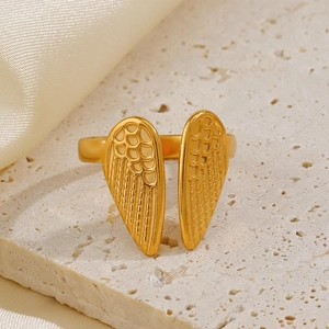 18K gold plated stainless steel angel wing ring on an elegant travertine stone stand