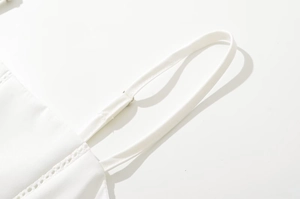 Detail of adjustable shoulder straps and delicate lace trim on white cotton dress