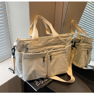 Detail view of beige corduroy tote bag showing front zipper pockets and adjustable strap