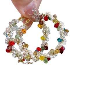 Boucles d'oreilles créoles perlées avec fil d'or et perles blanches sur fond blanc