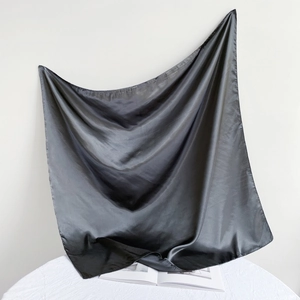 Detail of a 90cm black satin silk square scarf with soft texture and glossy finish