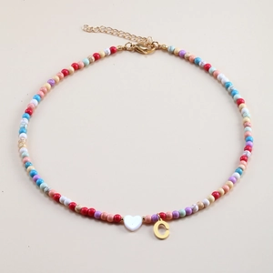 Detail of colorful beaded necklace with white heart charm and golden letter C pendant