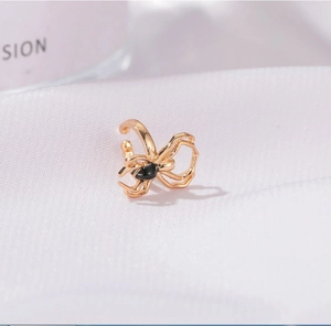 Macro view of gold spider ear cuff with black enamel detailing on white fabric
